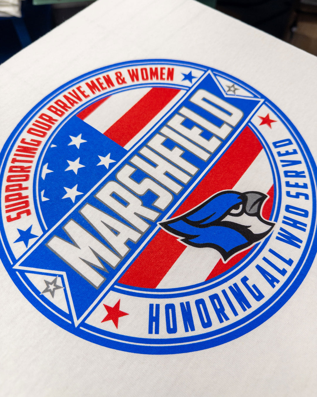Logo with 'Marshfield' text and American flag design on a white for Marshfield School